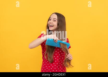 Happy Kid Kämmen lange Haare. Friseur. Mädchen hat wellige Frisur halten Haarbürste. Teen Schönheit Frisur Stockfoto