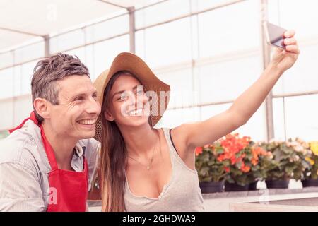 Ein paar Blumenverkäufer machen ein lustiges Selfie im Gewächshaus Stockfoto