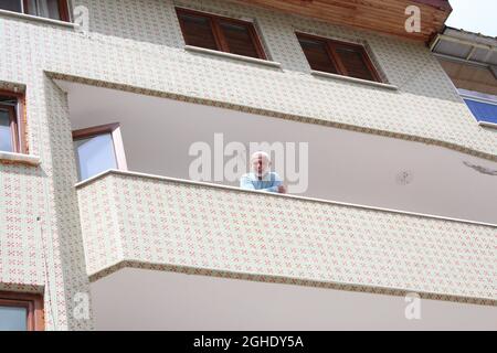 Älterer islamischer Mann, der vom Balkon zur Kamera lächelt und Glück verbreitet. Stockfoto