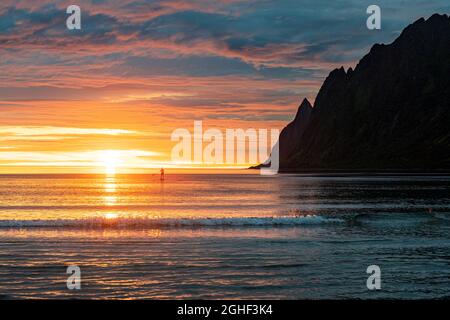 Mann auf Stand Up Paddle Board, der von warmen Lichtern der Mitternachtssonne, Ersfjord, Senja, Troms County, Norwegen, getroffen wurde Stockfoto