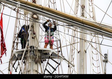 Saint John, NB, Kanada - 20. August 2017: Zwei Besatzungsmitglieder arbeiten an einem nebligen, bewölkten Tag in einem großen Laden hoch oben im Rigging. Viele Seile usw. Stockfoto