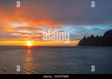 Die Mitternachtssonne spiegelte sich im Meer mit den Teufelszähnen-Berggipfeln im Hintergrund, Tungeneset, Senja, Troms County, Norwegen Stockfoto