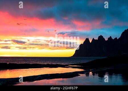 Scharfe Berggipfel unter dem dramatischen Himmel der Mitternachtssonne, Aussichtspunkt Tungeneset, Insel Senja, Kreis Troms, Norwegen Stockfoto