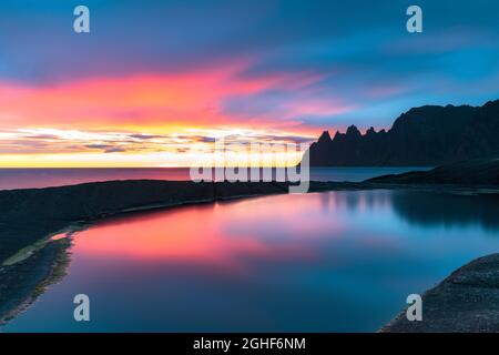 Lange Exposition des Meeres durch warme Lichter der Mitternachtssonne vom Aussichtspunkt Tungeneset, Senja, Troms County, Norwegen gefärbt Stockfoto