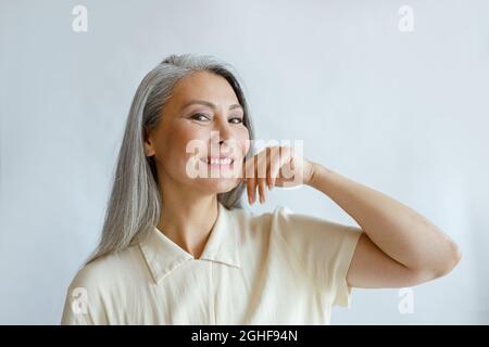 Elegante Frau mittleren Alters mit Hufhaar Posen auf hellem Hintergrund Stockfoto