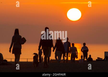 West Bay, Dorset, Großbritannien. September 2021. Wetter in Großbritannien. Die Strandbesucher werden im Badeort West Bay in Dorset nach einem Tag glühender, heißer Sonne während einer Mini-Hitzewelle vor einem goldorangen Sonnenuntergang geschildet. Bildnachweis: Graham Hunt/Alamy Live News Stockfoto