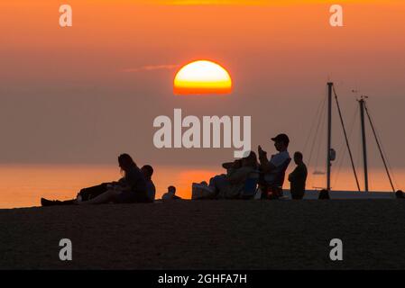 West Bay, Dorset, Großbritannien. September 2021. Wetter in Großbritannien. Die Strandbesucher werden im Badeort West Bay in Dorset nach einem Tag glühender, heißer Sonne während einer Mini-Hitzewelle vor einem goldorangen Sonnenuntergang geschildet. Bildnachweis: Graham Hunt/Alamy Live News Stockfoto