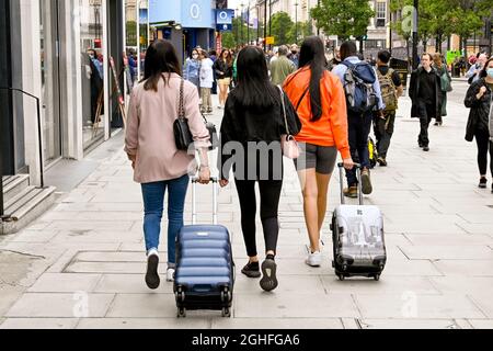 London, England - 2021. August: Junge Leute ziehen Koffer auf der Oxford Street im Zentrum Londons Stockfoto