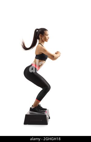 In voller Länge Profilaufnahme einer jungen Frau, die Step Aerobic auf weißem Hintergrund trainiert Stockfoto