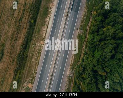 Ein Blick von oben auf eine leere asphaltierte Straße in die Landschaft. Luftbild Landschaft. Stockfoto