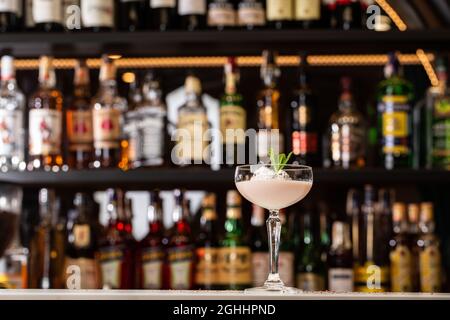 Ein Glas eisgekühlter Baileys-Cocktail, der in einem Glas serviert wird und mit Minzblättern dekoriert ist, die auf einer Bar platziert sind Stockfoto