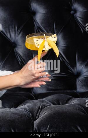 Frauenhand mit Sommercocktail - pornstar Martini. Trinken Sie mit Passionsfrucht, Vodka, Likör, Vanillesirup, Champagner und Limettensaft. Stockfoto
