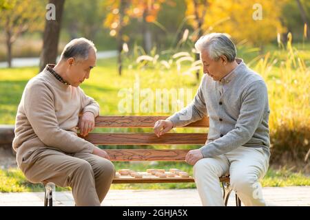 Fröhliche ältere Männer spielen chinesisches Schach Stockfoto