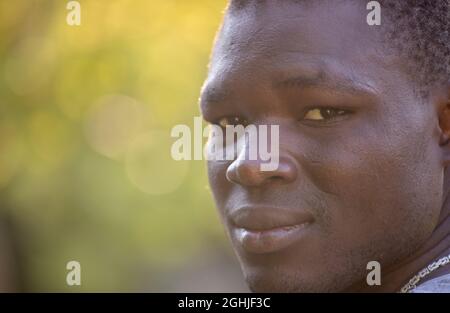 Porträt eines ernsthaften jungen afrikanischen Mannes mit besorgten Augen, der im Park steht Stockfoto