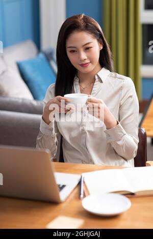 Junge Frau trinkt Kaffee zu Hause Stockfoto