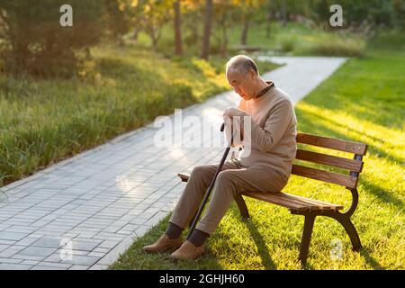 Einsamer älterer Mann, der auf der Parkbank sitzt Stockfoto