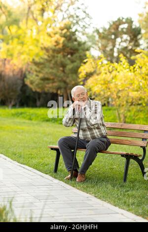 Einsamer älterer Mann, der auf der Parkbank sitzt Stockfoto