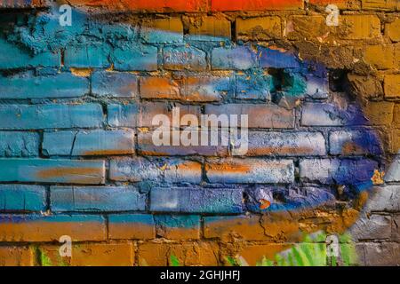 Raue verputzte Ziegelwand mit Rissen. Malen Sie Splash, bunten Hintergrund, Textur, Kopierraum Stockfoto