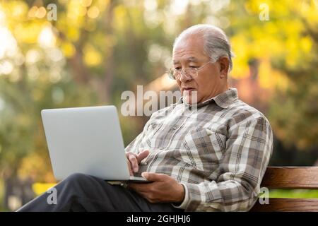 Älterer Mann mit Laptop im Park Stockfoto