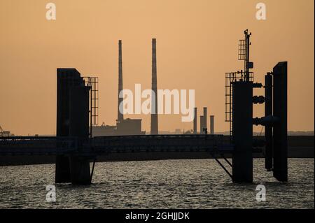 Teleansicht Poolbeg CCGT Schornsteine und Pigeon House Powers Station zwischen den Flügelwänden des Fährterminals am Pier von St. Michael im Hafen von Dun Laoghaire Stockfoto