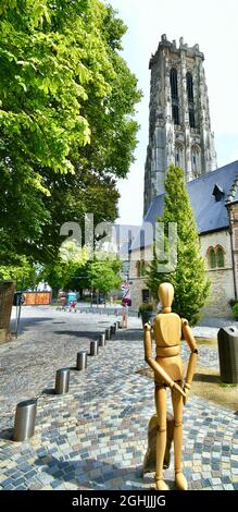 MECHELEN, BELGIEN - 12. Aug 2021: Prachtvolles Foto des gigantischem Turms der Kathedrale von Saint Rumbold mit im Vordergrund einer Holzpuppe Stockfoto