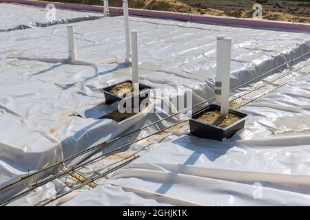 Kunststoff-Dampfsperre auf der Platte mit PVC-Rohrleitungen des Fundaments Stockfoto