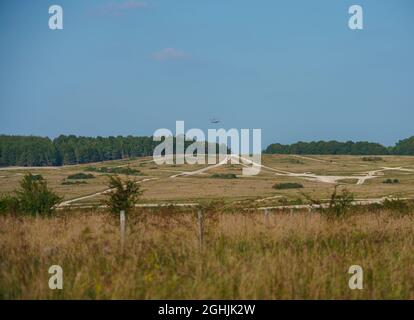 Blick über das Militärtrainingsgebiet Sidbury Hill mit einem AgustaWestland Merlin AW101 Hubschrauber, der in der Ferne fliegt, Wiltshire UK Stockfoto