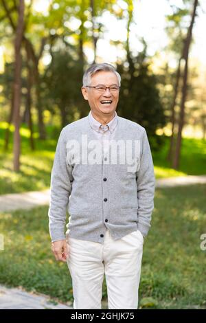 Fröhlicher älterer Mann, der sich im Park entspannt Stockfoto