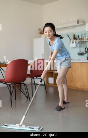 Fröhliche junge Frau, die Hausarbeit leistet Stockfoto