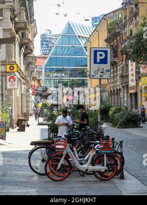 MAILAND, ITALIEN - 08. Aug 2021: Moderne Mobilität und Transport in Mailand Italien, Elektroroller und Fahrräder, Fahrräder im Besitz oder Verleih, in der geparkt Stockfoto