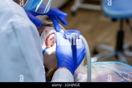 Zahnarzt, der mit dem Patienten aus der Nähe arbeitet. Das Mädchen sitzt auf dem Zahnarztstuhl. Stockfoto