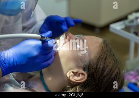 Mädchen mit Brille behandelt Vorderzähne. Hände eines Zahnarztes. Zahnpolieren. Stockfoto