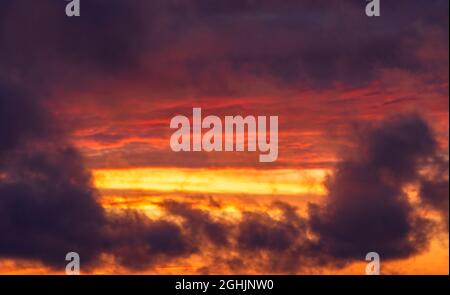 Strahlender Sonnenuntergang vor dem Sturm. Gelbe und lila Wolken bei Sonnenuntergang, Ort für Text, Textur für Hintergrundbild Stockfoto