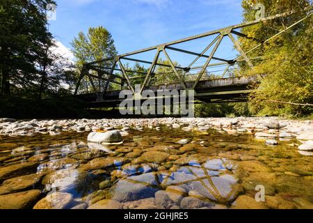 Carnation, WA, USA - 06. September 2021; Tolt River, der im Sommer unter der State Route 203 Brücke in Carnation Washington passiert. Flussfelsen sind expos Stockfoto