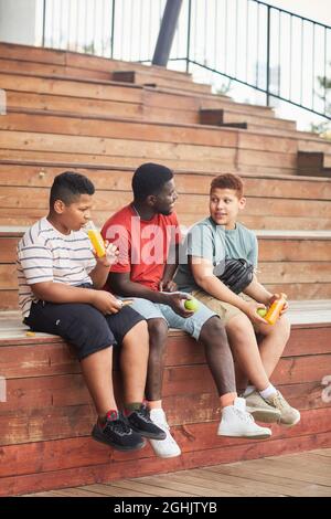 Afroamerikanische Fanfamilie, bestehend aus Vater und Söhnen, die auf Ständen sitzen und sich unterhalten Stockfoto