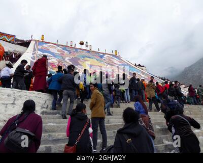 Menschen, die am Fuße des riesigen Thangka-Gemäldes des Maitreya Buddha im Kloster Drepung, Berg Gephel, Lhasa, Tibet, Respekt zollen - Aug 2014 Stockfoto