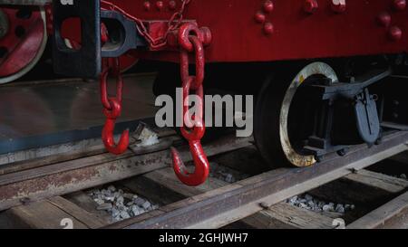 Nahaufnahme der Räder eines roten Zuges auf einem hölzernen Bahnhof Stockfoto