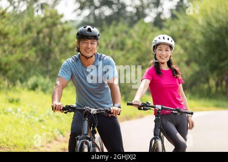 Glückliches reifes Paar, das Fahrräder im Park fährt Stockfoto