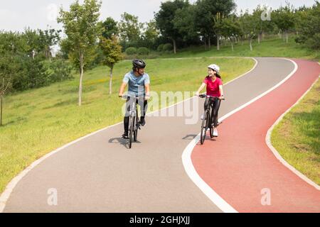 Glückliches reifes Paar, das Fahrräder im Park fährt Stockfoto