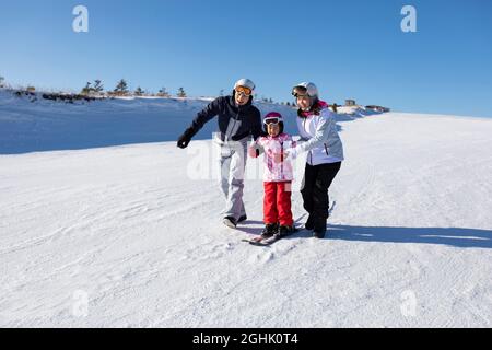 Junge Eltern lehren Tochter Skifahren Stockfoto