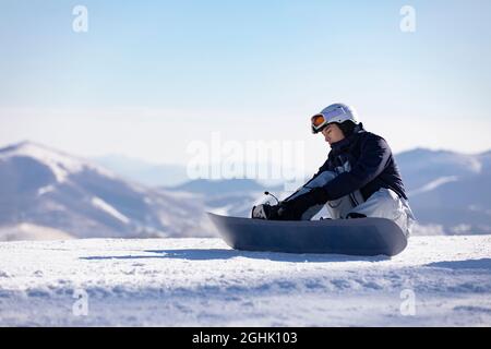 Junger Mann mit Snowboard auf dem Schnee Stockfoto