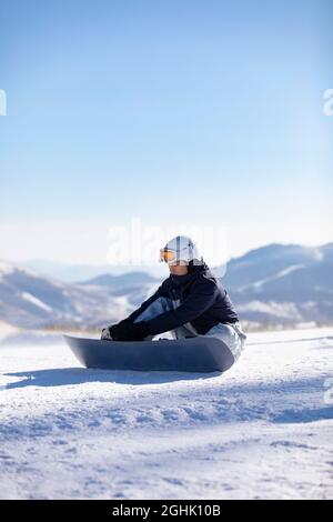 Junger Mann mit Snowboard auf dem Schnee Stockfoto