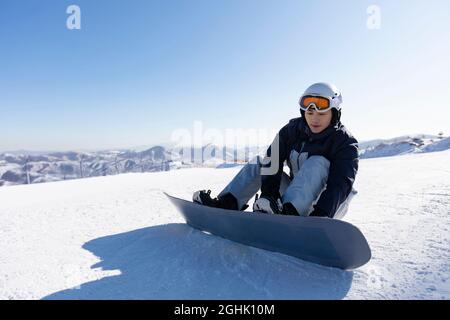 Junger Mann mit Snowboard auf dem Schnee Stockfoto