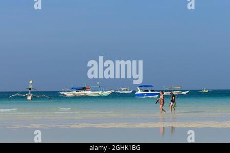 Ein Paar, das im seichten Meerwasser am Bulabog Beach in Boracay auf den Philippinen spazierengeht. Stockfoto