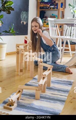 Teenager Mädchen spielen Track Konstruktor Block Turm mit metallischen Ball Maria Montessori Materialien Stockfoto