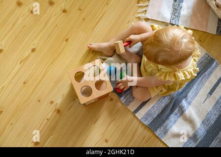 Happy girl Kleinkind Schlagen Holzhammer auf farbigen Kugeln frühe Entwicklung ökologischen Spielzeug Stockfoto