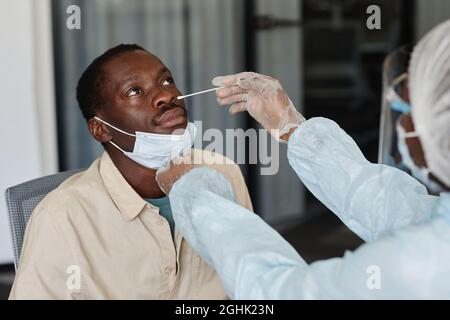 Afroamerikanischer Mann, der einen Arzt wegen eines Nasenabstrichs besucht, um einen Coronavirus-Labortest zu erhalten Stockfoto