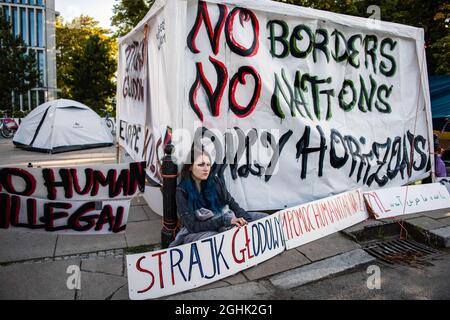 Warschau, Polen. September 2021. Während des Protestes sitzt ein Aktivist auf dem Bürgersteig, umgeben von flüchtlingsfreundlichen Plakaten.das polnische Parlament hat heute Abend formell den Ausnahmezustand in zwei an Weißrussland angrenzenden Regionen genehmigt - die erste Ordnung dieser Art seit den kommunistischen Tagen Polens. Viele der wichtigsten Oppositionsparteien Polens haben den Ausnahmezustand kritisiert und argumentiert, dass es sich um eine Überreaktion handelt, die die bürgerlichen Freiheiten eindämmerte. Kredit: SOPA Images Limited/Alamy Live Nachrichten Stockfoto