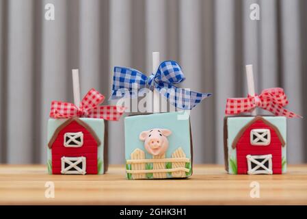 Quadratischer Lutscher aus Schokolade im Bauernstil. Süßigkeiten mit Marzipan in Form von Tieren hinter dem Zaun - Schwein, Pferd und Kuh dekoriert. Stockfoto