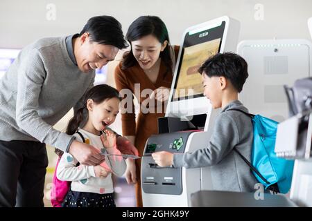 Eine glückliche junge Familie, die am Flughafen selbst einchecken kann Stockfoto